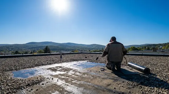 Szigetelő bitumenes folttal javít egy kavicsos lapostetőt, a felületen pangó víz